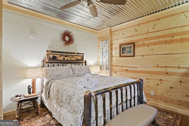 bedroom with ceiling fan, wood walls, and wood finished floors