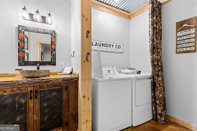 laundry area with baseboards, separate washer and dryer, and a sink