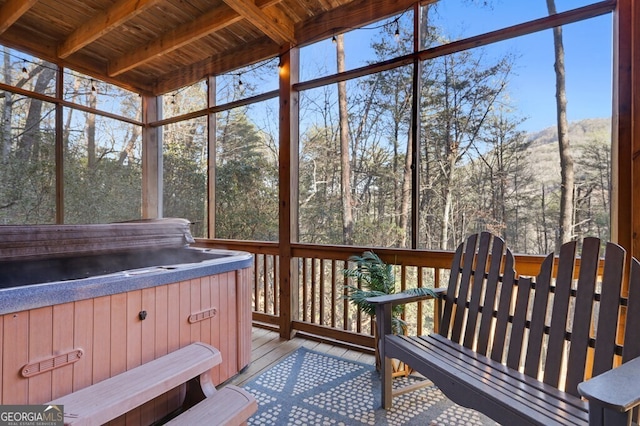 sunroom / solarium with beam ceiling and a hot tub