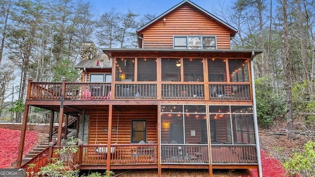 back of house with a sunroom, faux log siding, and stairway