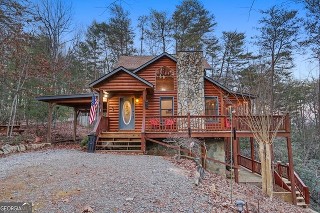 view of front of house featuring gravel driveway, a shingled roof, an attached carport, and a wooden deck