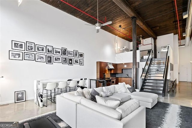 living room with wood ceiling, ceiling fan, concrete floors, and a high ceiling