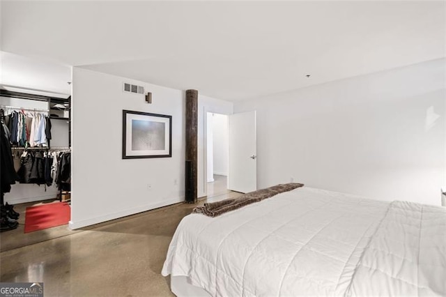 bedroom with concrete flooring, a closet, and a spacious closet