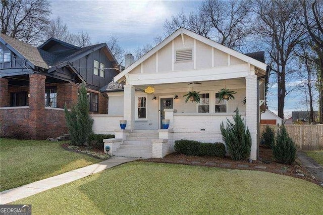 view of front facade with ceiling fan, covered porch, and a front lawn