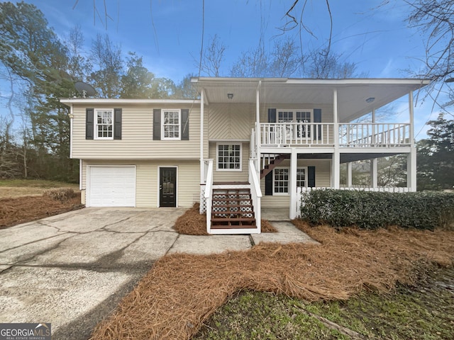 bi-level home featuring a porch, stairway, an attached garage, a balcony, and driveway