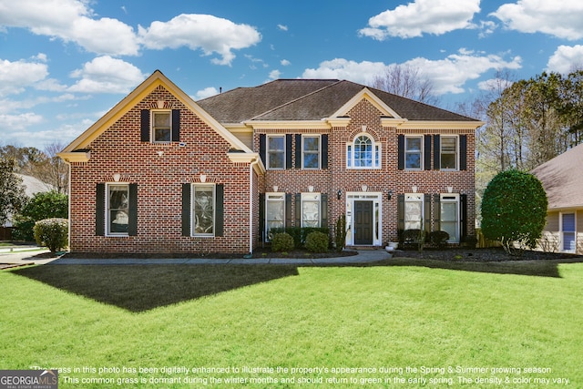 colonial inspired home featuring brick siding, roof with shingles, and a front yard