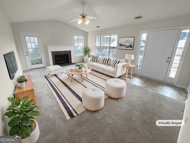 living room with carpet floors, a fireplace, visible vents, vaulted ceiling, and ceiling fan