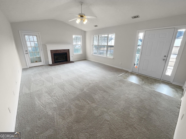 unfurnished living room featuring light carpet, visible vents, a ceiling fan, vaulted ceiling, and a brick fireplace