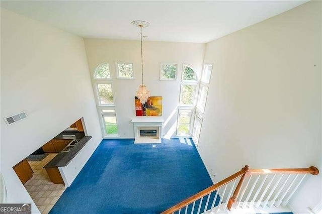 living room with a towering ceiling and dark colored carpet