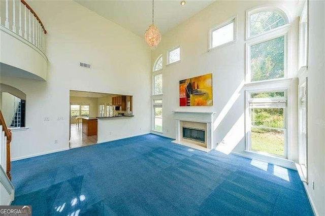 unfurnished living room with dark carpet and a towering ceiling