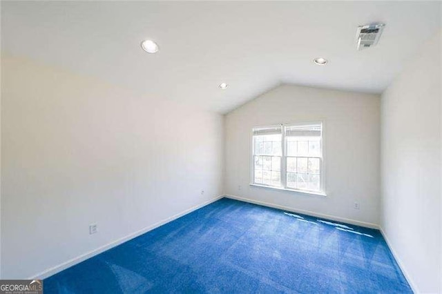 carpeted empty room featuring vaulted ceiling