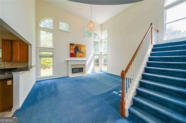 living room with a towering ceiling and dark colored carpet