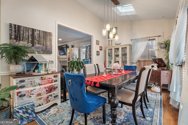 dining space with wood-type flooring and vaulted ceiling with skylight