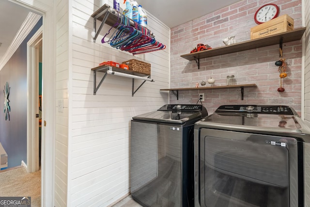 clothes washing area featuring washing machine and dryer, brick wall, and carpet flooring