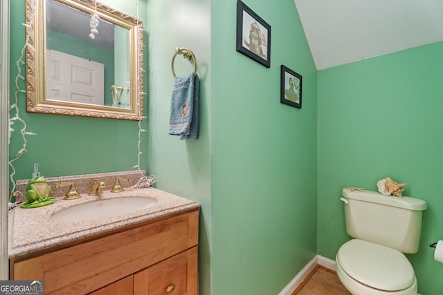 bathroom featuring vanity, vaulted ceiling, tile patterned floors, and toilet