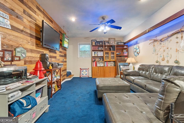 carpeted living room featuring ceiling fan and wood walls