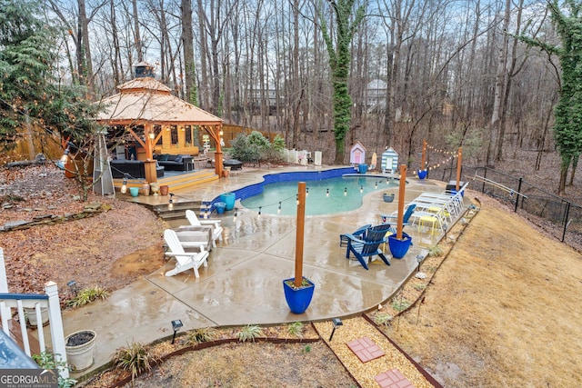 view of swimming pool featuring a gazebo, a wooden deck, and a storage unit