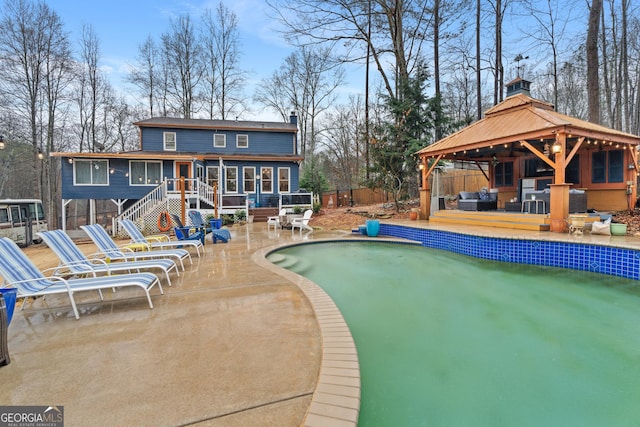 view of swimming pool featuring a patio area, a gazebo, a wooden deck, an outdoor hangout area, and a sunroom