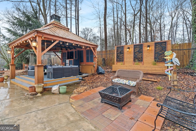 view of patio with a gazebo, a deck, and an outdoor living space with a fire pit