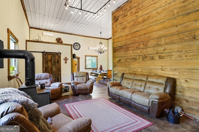 living room featuring a barn door, track lighting, a notable chandelier, and wooden walls