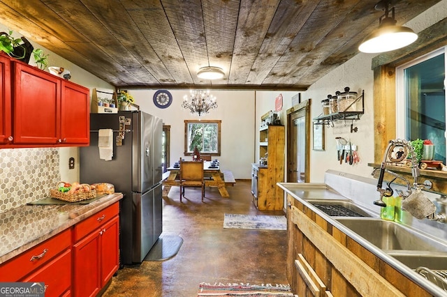 kitchen featuring stainless steel refrigerator, sink, backsplash, wood ceiling, and an inviting chandelier