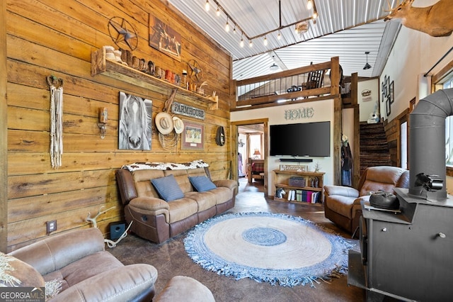 living room with a high ceiling, track lighting, and wooden walls