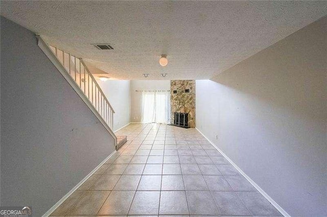 interior space featuring a fireplace, a textured ceiling, and light tile patterned flooring