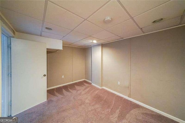 basement with a paneled ceiling and carpet