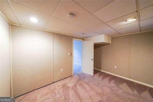 basement with a paneled ceiling and carpet flooring