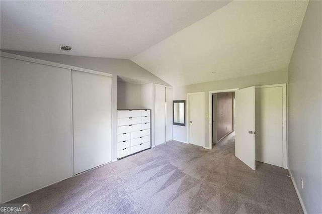 unfurnished bedroom featuring lofted ceiling, carpet floors, a closet, and a textured ceiling