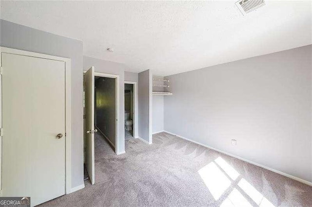 unfurnished bedroom featuring light colored carpet, a textured ceiling, and a closet