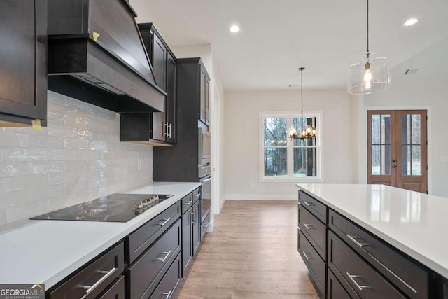 kitchen with premium range hood, hanging light fixtures, black electric stovetop, light hardwood / wood-style floors, and oven