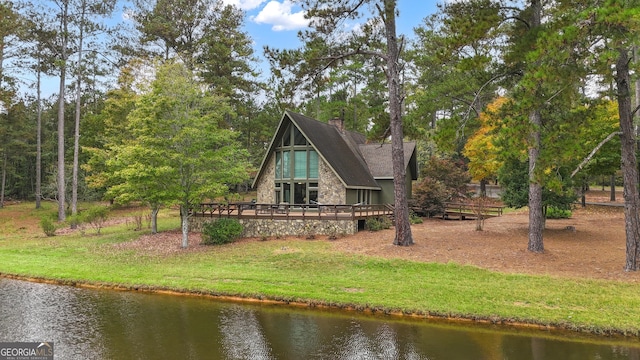 back of property featuring a chimney, stone siding, a lawn, and a deck with water view