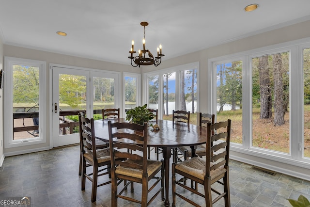 sunroom / solarium with a wealth of natural light, visible vents, a notable chandelier, and a water view