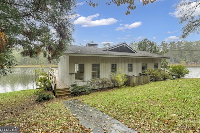 view of side of home with board and batten siding, a water view, and a lawn