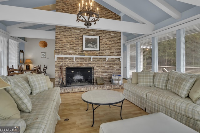 living room with vaulted ceiling with beams, a notable chandelier, a fireplace, and light wood-style flooring