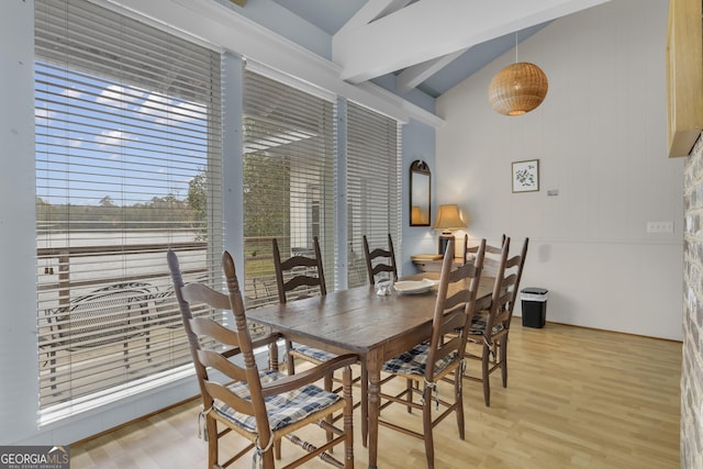 dining space with lofted ceiling with beams and light wood finished floors