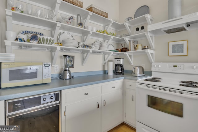 kitchen featuring open shelves, white appliances, white cabinetry, and under cabinet range hood