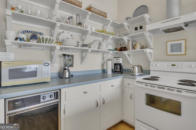 2724 Barnesville Hwy, Thomaston, GA 30286 - kitchen featuring white appliances, open shelves, wall chimney exhaust hood, light wood-style flooring, and white cabinetry