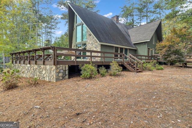 exterior space with a chimney, roof with shingles, and a deck