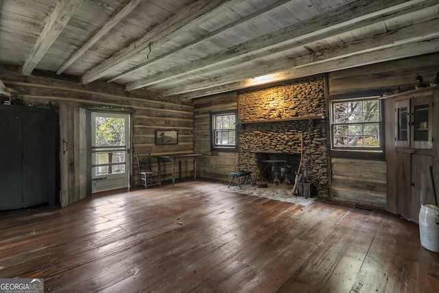 unfurnished living room featuring dark wood-style floors, a stone fireplace, wooden ceiling, and beam ceiling