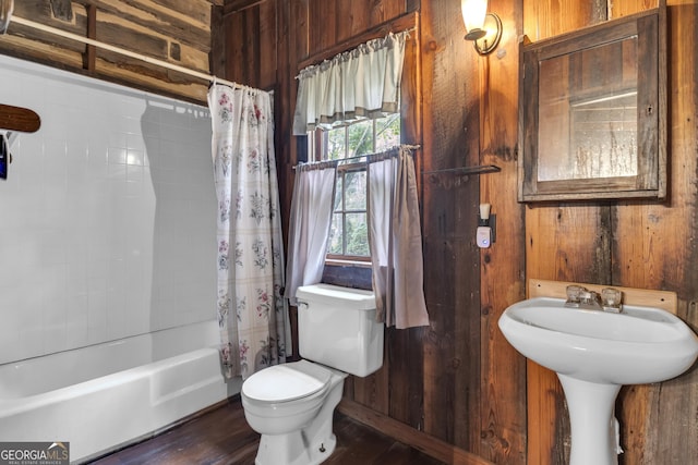 bathroom featuring toilet, shower / tub combo, wood finished floors, and wood walls