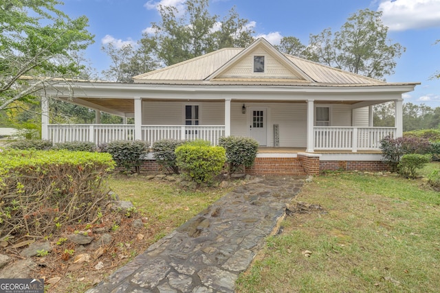 country-style home with a porch, a front yard, and metal roof