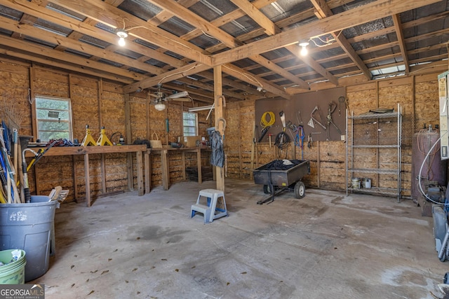 miscellaneous room with a garage, unfinished concrete flooring, and a workshop area