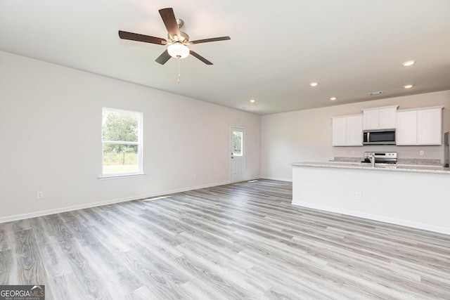 kitchen featuring a healthy amount of sunlight, appliances with stainless steel finishes, light stone countertops, and white cabinets