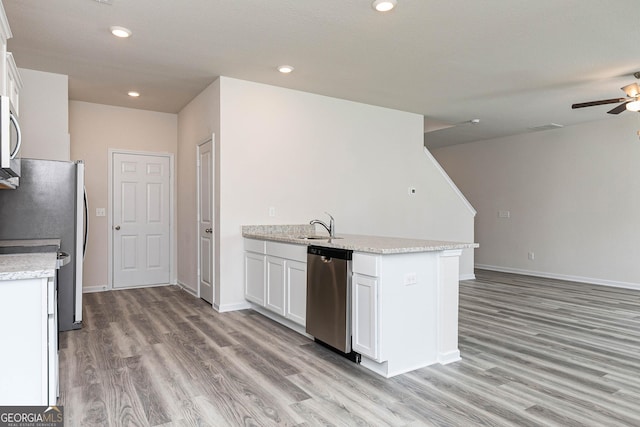 kitchen with stainless steel appliances, light stone counters, white cabinets, and light hardwood / wood-style floors