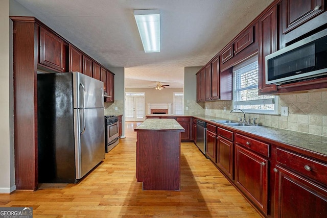 kitchen featuring sink, light hardwood / wood-style flooring, appliances with stainless steel finishes, backsplash, and a center island