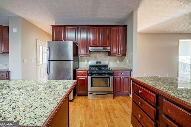 kitchen with tasteful backsplash, a textured ceiling, light wood-type flooring, stainless steel appliances, and range hood