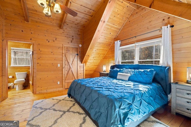 bedroom with ensuite bathroom, lofted ceiling with beams, wooden ceiling, wooden walls, and light hardwood / wood-style floors