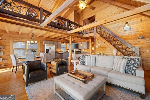 living room with beam ceiling, light hardwood / wood-style flooring, high vaulted ceiling, and wood walls